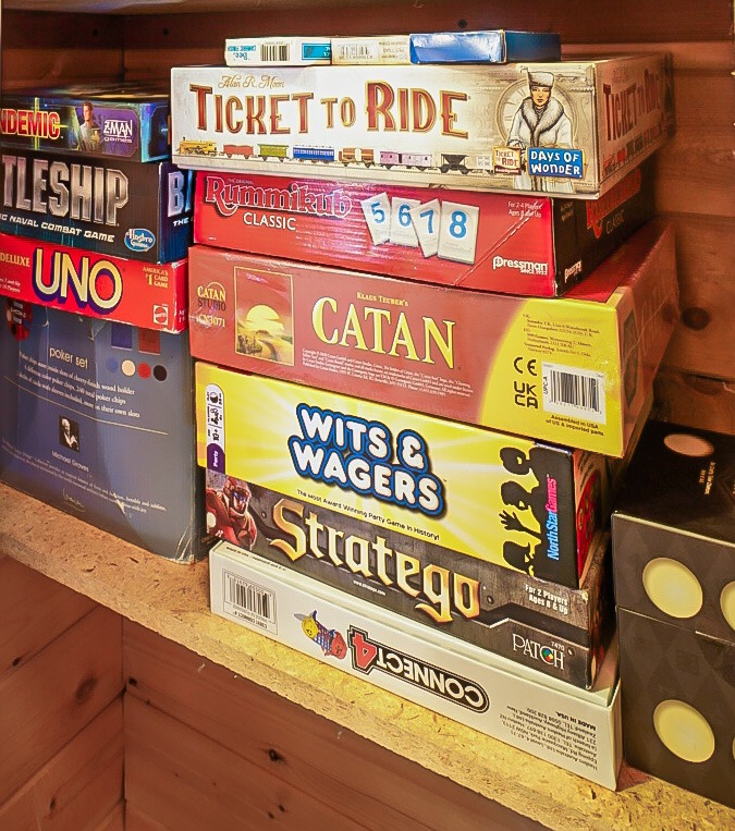 Shelf stacked with board games including Catan, Ticket to Ride and Uno
