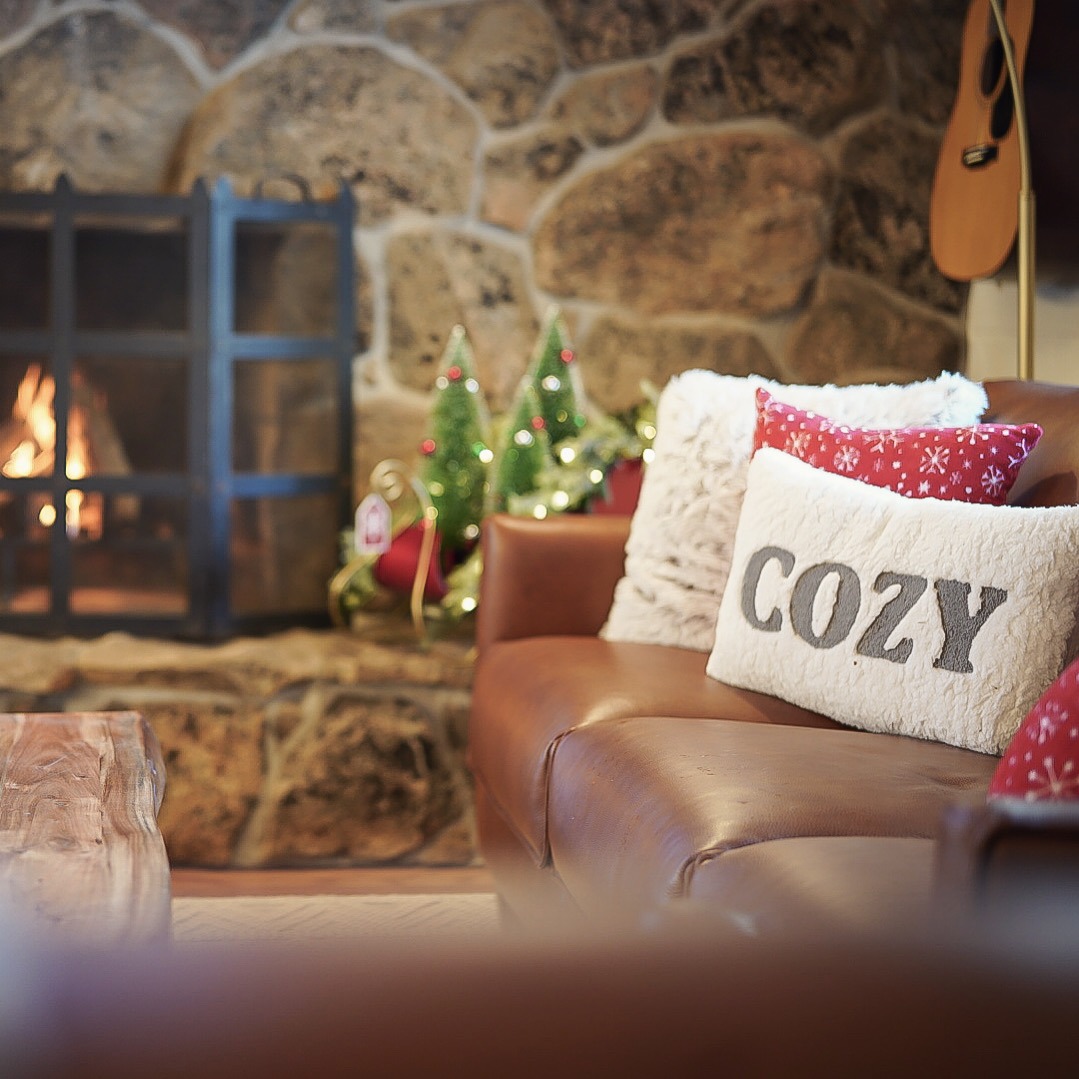 Cozy pillow and leather sofa beside the lit stone fireplace at the holidays