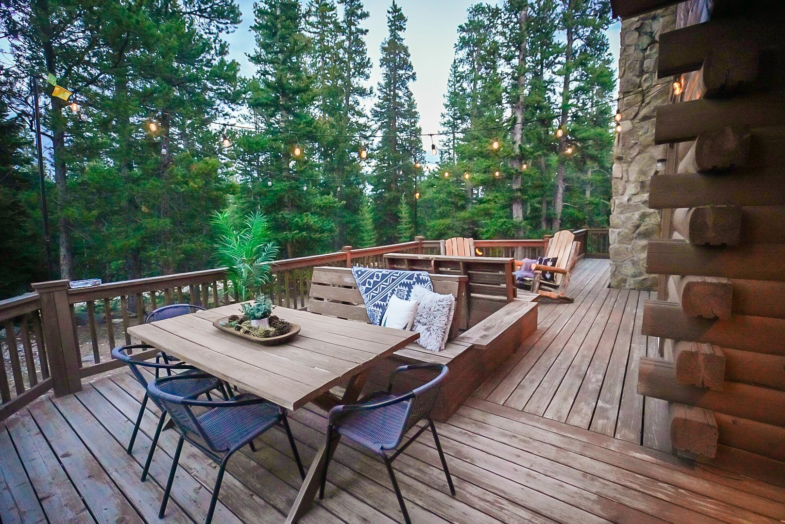 Wraparound deck with outdoor dining surrounded by pines