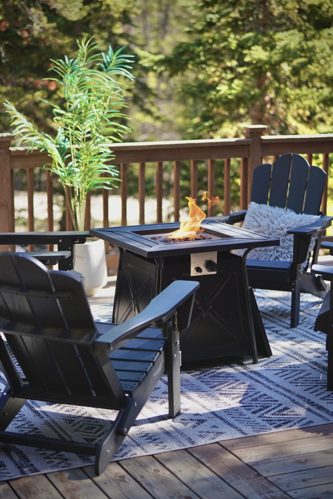 Gas fire pit surrounded by Adirondack chairs on the sunny deck