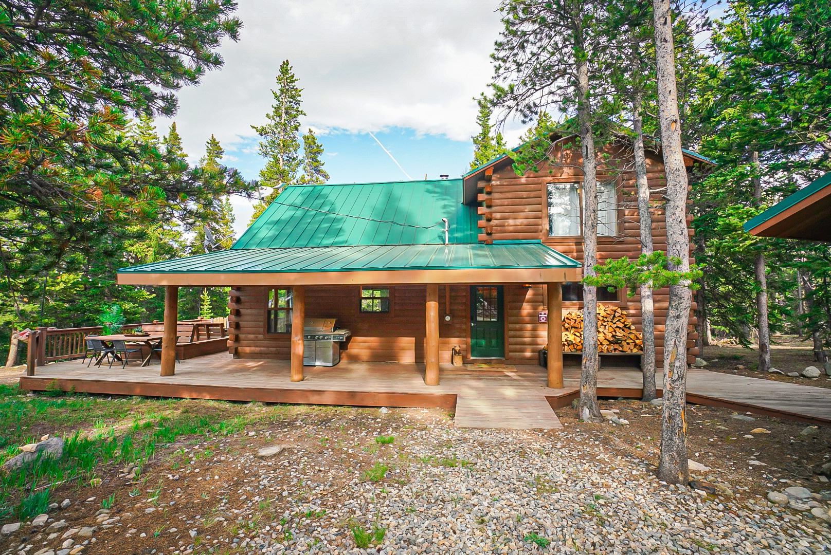 Timber Valley Lodge log cabin with green metal roof and lit deck at dusk