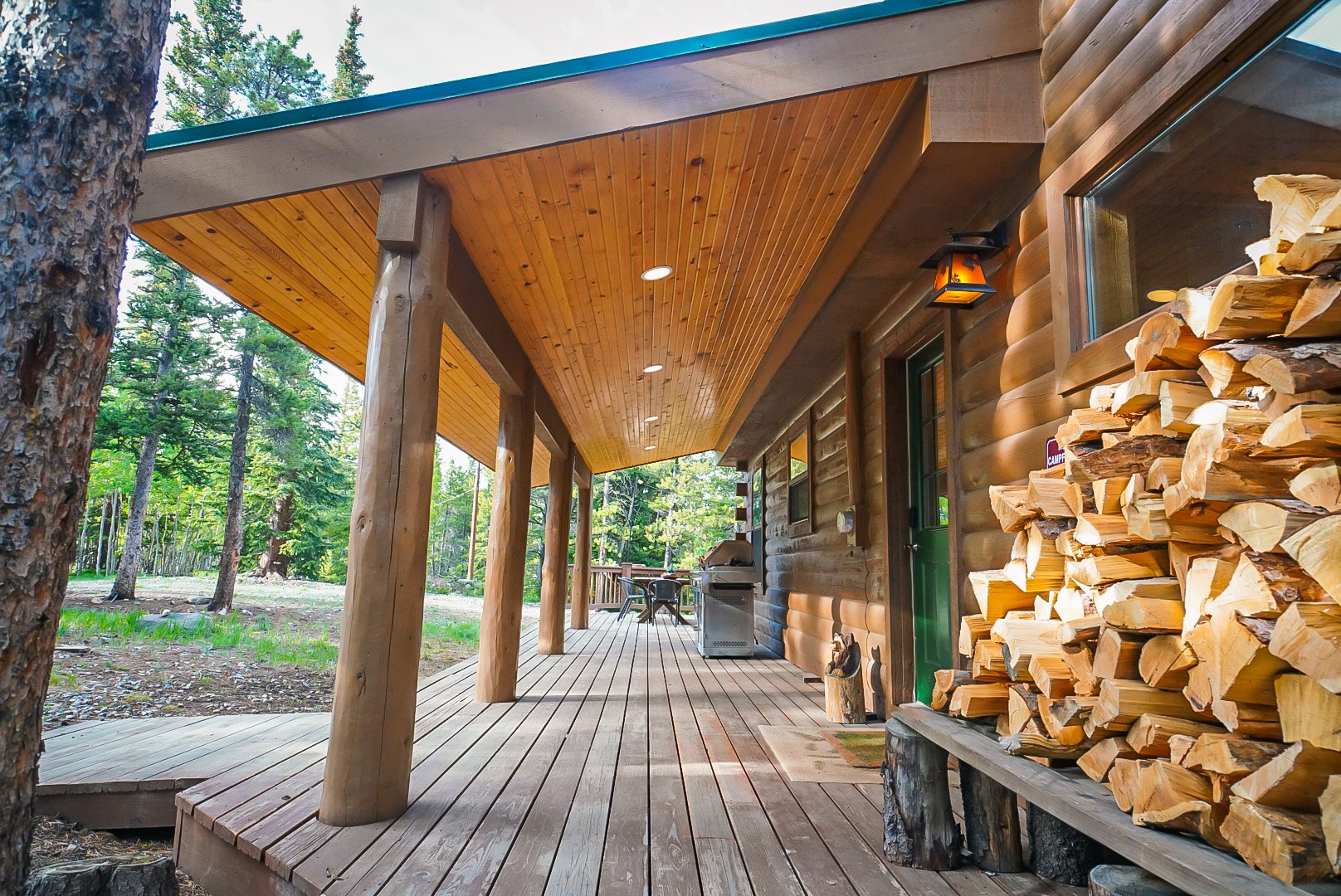 Covered porch with log posts and stacked firewood