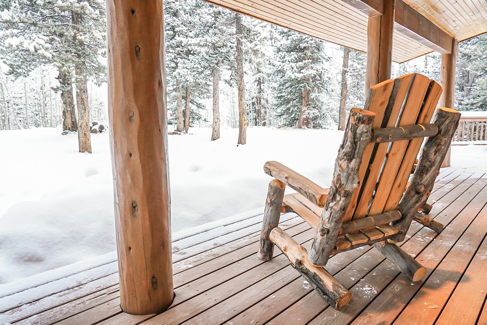 Log Adirondack chair on the porch looking out over fresh snow