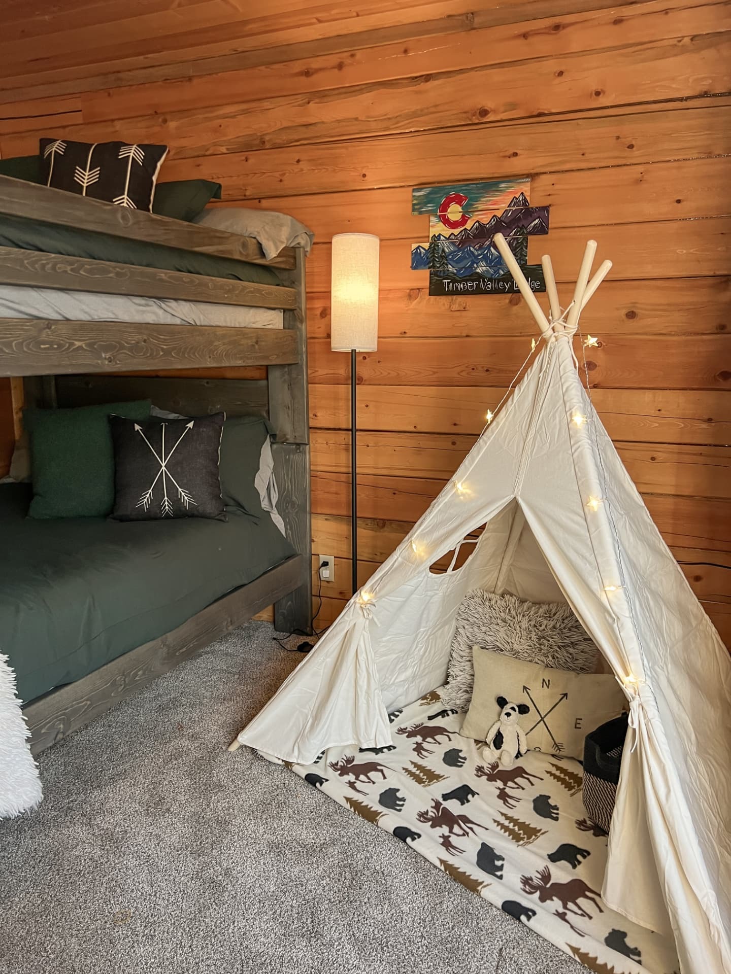 Bunk room with a lit teepee play tent in the corner
